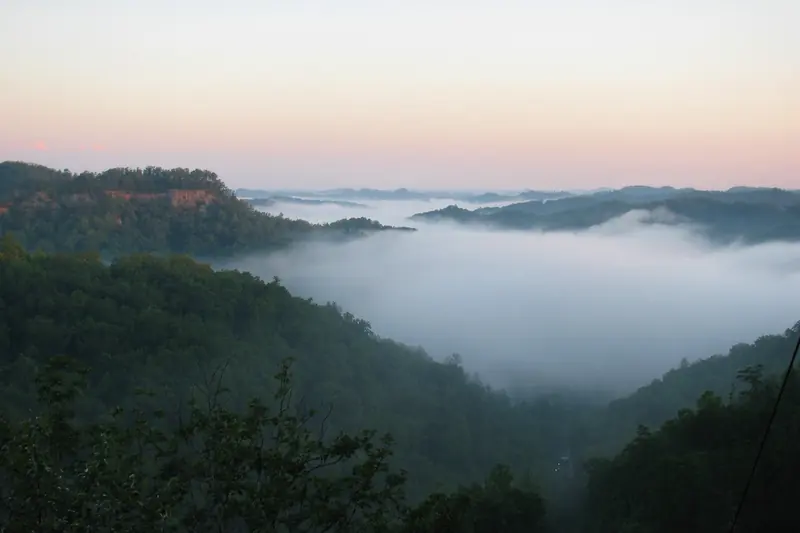 Dawn fog filling a valley between wooded Kentucky hills