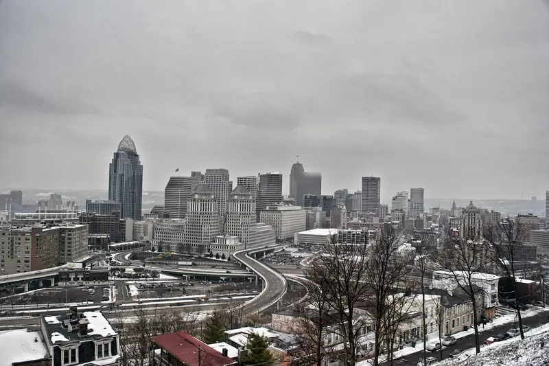 Snow-dusted rooftops and office towers of a river city on an overcast winter day